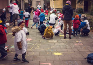 Dzieci rysują kredą na chodniku przed przedszkolem